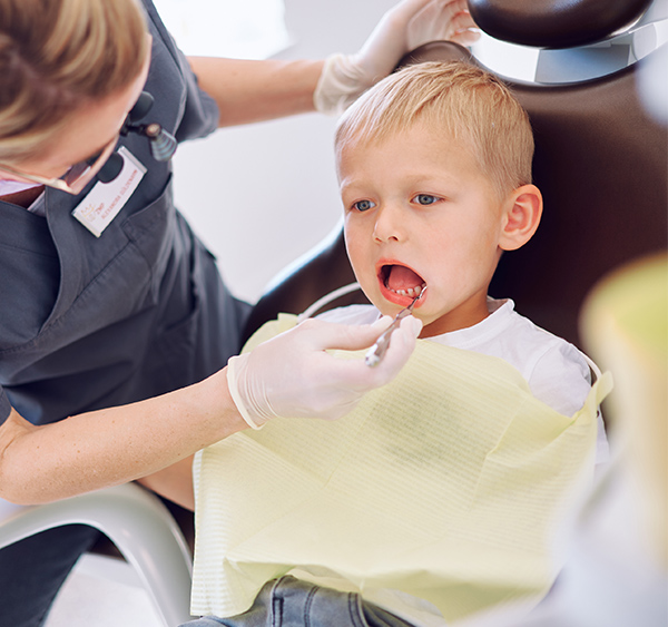 Mitarbeiterin mit Instrument im Munde eines kleinen Jungen